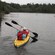 2 Guests in a 2 seat canoe paddling on a forested lake